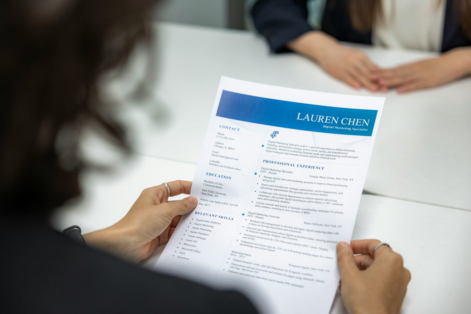 An interviewer reading a candidate's résumé across a desk during a job interview